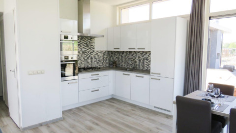 Moderne keuken met witte kasten en mozaïektegels, Pavilion at Zuiderzee, Nederland, met eetgedeelte ernaast.