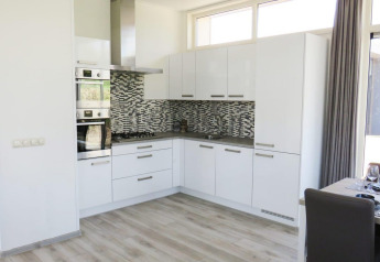 Moderne keuken met witte kasten en mozaïektegels, Pavilion at Zuiderzee, Nederland, met eetgedeelte ernaast.