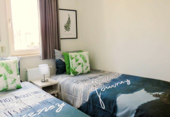 Deux lits simples au Pavilion at Zuiderzee, Pays-Bas, oreillers verts et intérieur moderne et lumineux.