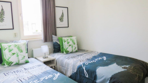 Twee enkele bedden bij Pavilion aan het Zuiderzee, groene kussens, lichte en moderne inrichting.