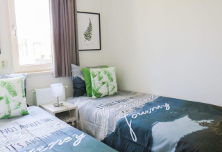 Twee enkele bedden bij Pavilion aan het Zuiderzee, groene kussens, lichte en moderne inrichting.