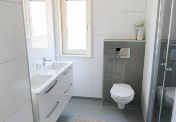 Moderne badkamer in Pavilion at Zuiderzee lodge in Nederland, met dubbele lavabo, zwevend toilet en douche.