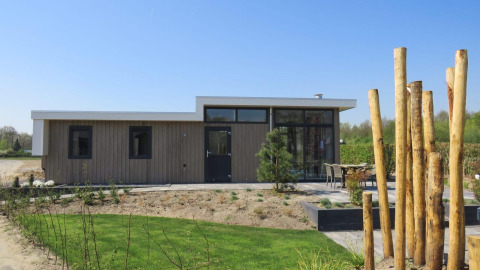 Moderne paviljoenlodge bij Zuiderzee in Nederland met houten gevel, terras en uitzicht op de tuin.