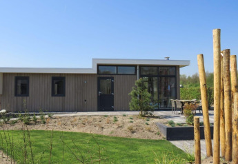 Modern paviljoenlodge aan de Zuiderzee in Nederland omgeven door tuin en terras met zitgelegenheid.