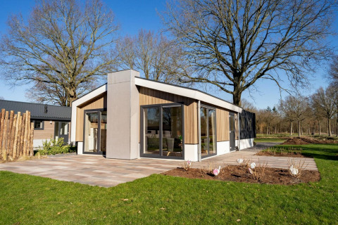 Chalet moderne avec de grandes fenêtres au Pavilion at Zuiderzee aux Pays-Bas, entouré de verdure et d’arbres.