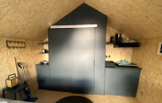Kitchenette moderne chez Solo Retreat 2 à Zuiderzee, Pays-Bas, meubles noirs et design minimaliste.