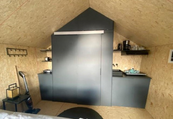 Moderne kitchenette in Solo Retreat 2 in Zuiderzee, Nederland, met zwarte kastjes en minimalistisch ontwerp.