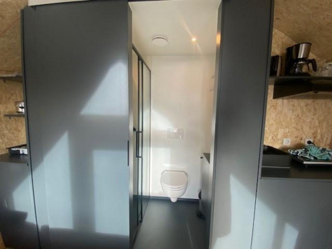 Binnenaanzicht van lodge Solo Retreat 2 bij Zuiderzee in Nederland, met zicht op toilet en keuken.