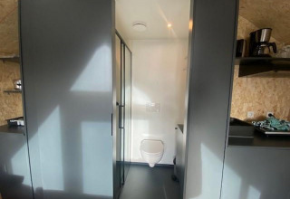 Binnenaanzicht van lodge Solo Retreat 2 bij Zuiderzee in Nederland, met zicht op toilet en keuken.