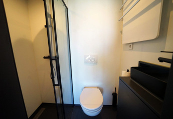 Moderne badeværelse med væghængt toilet, sort bruser og vask på Solo Retreat 2, Zuiderzee, Holland.
