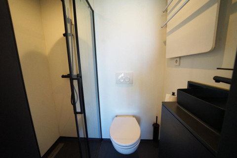 Moderne badkamer met wandtoilet, zwarte douche en wastafel in Solo Retreat 2, Zuiderzee, Nederland.