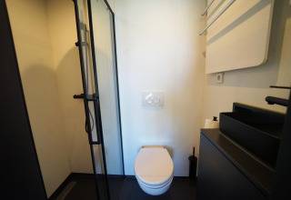 Bagno moderno con wc sospeso, doccia e lavabo neri al Solo Retreat 2, Zuiderzee, Paesi Bassi.