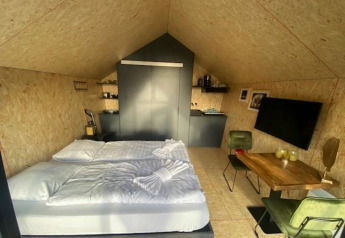 Indvendigt billede af Solo Retreat 2-lodgen i Zuiderzee, Holland, med seng, spisebord og tekøkken.