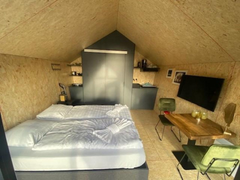 Interieur van Solo Retreat 2 lodge in Zuiderzee, Nederland, met bed, eettafel, tv en keukentje.