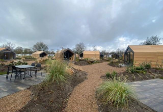 Buitenaanzicht van meerdere Solo Retreat 2-lodges bij Zuiderzee in Nederland, met paden en tuinen.