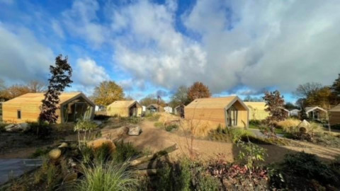 Holzhütten im Solo Retreat 2 bei Zuiderzee in den Niederlanden, umgeben von Natur und blauem Himmel.