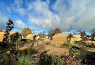 Holzhütten im Solo Retreat 2 bei Zuiderzee in den Niederlanden, umgeben von Natur und blauem Himmel.