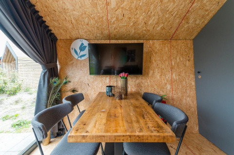 Coin repas moderne au Solo Retreat 4 de Zuiderzee, Pays-Bas, avec table en bois et télévision murale.