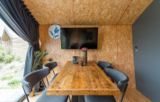 Moderne spiseplads i Solo Retreat 4-lodgen på Zuiderzee, Holland, med træbord og TV på væggen.