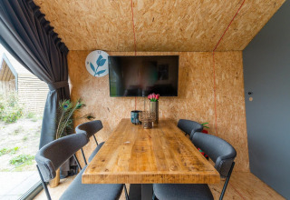 Coin repas moderne au Solo Retreat 4 de Zuiderzee, Pays-Bas, avec table en bois et télévision murale.