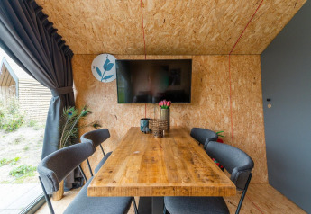 Moderne eetruimte in Solo Retreat 4 op Zuiderzee, Nederland, met houten tafel en tv aan de wand.