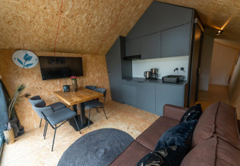 Eigentijds lodge-interieur met keukenblok, eettafel, zetel en tv bij Solo Retreat 4 aan de Zuiderzee, Nederland.
