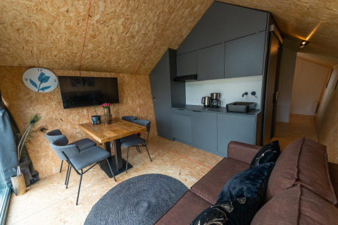 Eigentijds lodge-interieur met keukenblok, eettafel, zetel en tv bij Solo Retreat 4 aan de Zuiderzee, Nederland.