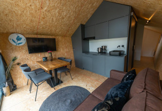 Eigentijds lodge-interieur met keukenblok, eettafel, zetel en tv bij Solo Retreat 4 aan de Zuiderzee, Nederland.