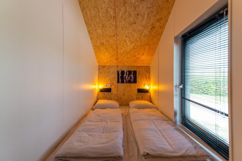 Gemütliches Schlafzimmer mit zwei Einzelbetten, Holzwand und großem Fenster im Solo Retreat 4, Zuiderzee.