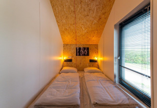 Acogedor dormitorio con dos camas, luces cálidas y ventana grande en Solo Retreat 4 en Zuiderzee, Países Bajos.