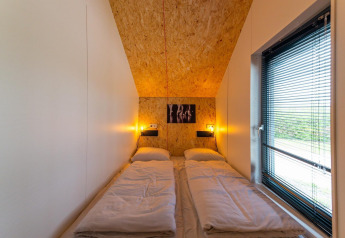 Knusse slaapkamer met twee losse bedden, warme verlichting en groot raam in Solo Retreat 4, Zuiderzee.