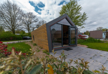 Moderne Solo Retreat 4 lodge bij Zuiderzee in Nederland met grote ramen en betegelde patio.