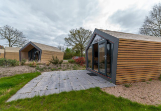 Moderne houten hutten bij Solo Retreat 4 in Zuiderzee, Nederland, omgeven door groen, onder bewolkte lucht.