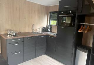 Kompakte moderne Küche in Tiny House 2, Zuiderzee, Niederlande, mit dunklen Schränken und Holzdekor.