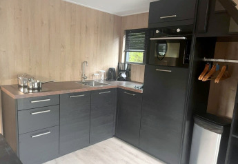 Petite cuisine moderne de Tiny House 2 à Zuiderzee, Pays-Bas, avec placards noirs et murs boisés.