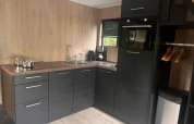 Moderne kitchenette in Tiny House 2 aan Zuiderzee, Nederland, met zwarte kasten en houten muren.