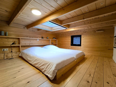 Holzverkleidetes Schlafzimmer mit Doppelbett und Dachfenster in Tiny House 2 bei Zuiderzee, Niederlande.