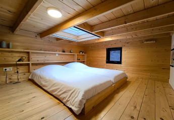 Chambre en bois avec lit double et fenêtre de toit dans Tiny House 2 à Zuiderzee, Pays-Bas.
