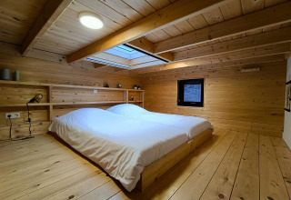 Camera da letto rivestita in legno con letto matrimoniale e lucernario in Tiny House 2 a Zuiderzee, Paesi Bassi.