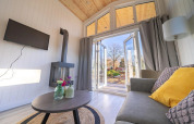 Helles Wohnzimmer in Tiny House 4 bei Zuiderzee, Niederlande, mit Sofa, Tisch und Blick auf Terrasse.
