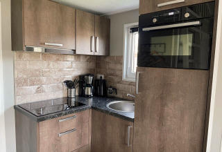 Moderne køkkenhjørne i Tiny House 4 ved Zuiderzee, Holland, med træskabe og køkkenudstyr.