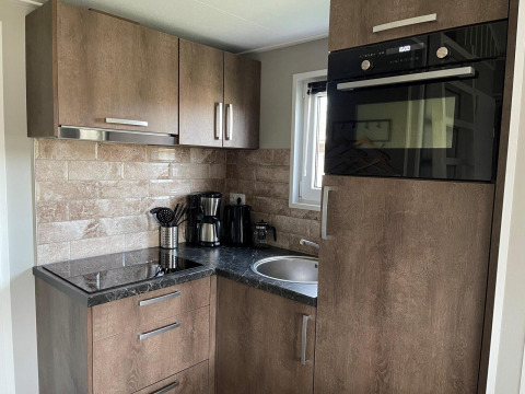 Moderne køkkenhjørne i Tiny House 4 ved Zuiderzee, Holland, med træskabe og køkkenudstyr.