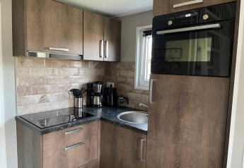 Moderne hoekkeuken in Tiny House 4 aan Zuiderzee, Nederland, met houten kasten en apparatuur.