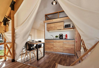 Modernes Glamping-Zelt mit Küchenzeile, Esstisch, Holzdetails und gemütlichem, offenem Interieur.