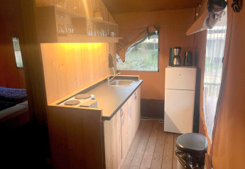 Keukenhoek in een Glampingtent 4 bij Zuiderzee, Nederland met koelkast, kookplaat en servies.