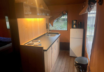 Angolo cottura in una Glampingtent 4 a Zuiderzee, Paesi Bassi, con piano cottura, lavello e frigo.