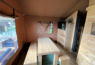 Interior de una tienda safari, Glampingtent 4, en Zuiderzee, Países Bajos, con mesa y bancos de madera.