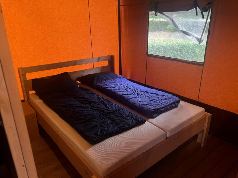Innenraum eines Safari-Glampingtents 4 bei Zuiderzee, Niederlande, mit zwei Einzelbetten und orange Plane.
