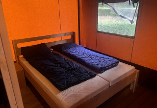 Innenraum eines Safari-Glampingtents 4 bei Zuiderzee, Niederlande, mit zwei Einzelbetten und orange Plane.