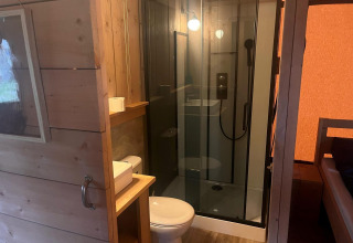 Badezimmer in einem Safarizelt bei Zuiderzee, Niederlande, mit Dusche, Toilette und Waschbecken.